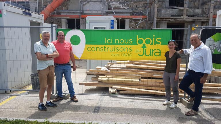 AOC Bois du Jura : banderole "ici nous construisons avec l'AOC Bois du Jura" devant l'école de la Chaux avec les élus de la commune